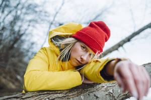 Serious young woman leaning on tree trunk - OLRF00140