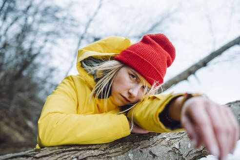 Ernste junge Frau lehnt sich an einen Baumstamm - OLRF00140