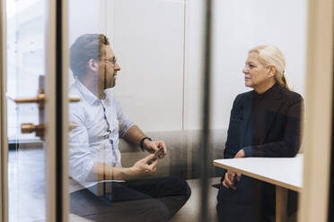 Ältere Geschäftsfrau bespricht sich mit einem Kollegen in einer Bürozelle - JOSEF23387