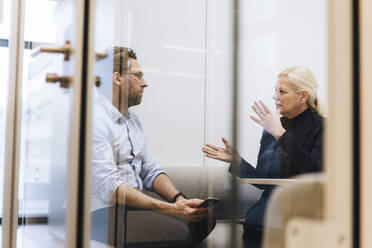 Businesswoman discussing with colleague in office cubical - JOSEF23389