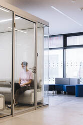 Young businesswoman working on laptop in office cubical - JOSEF23415