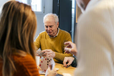 Friends playing cards together at home - PBTF00455