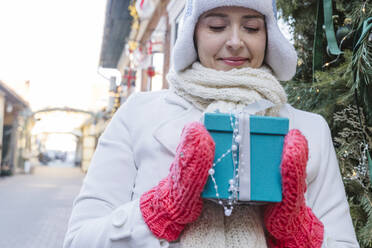 Woman looking at decorated gift box in Christmas - OSF02388