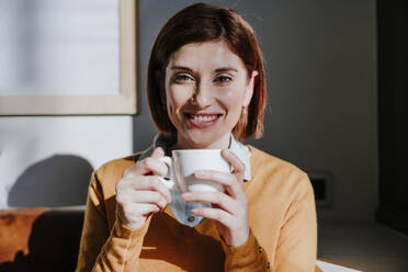 Lächelnde Frau mit Kaffeetasse in einem Cafe - EBBF08438