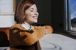 Happy woman enjoying sunlight in cafe - EBBF08446