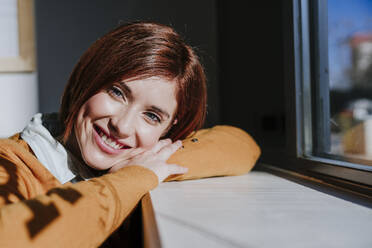 Smiling woman enjoying sunlight in cafe - EBBF08449