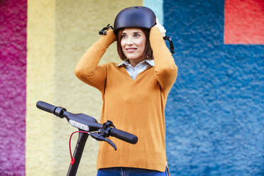 Lächelnde Frau mit Helm vor einer mehrfarbigen Wand - EBBF08484