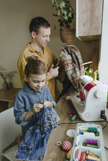 Vater und Tochter recyceln alte Kleidung zu Hause - YTF01786