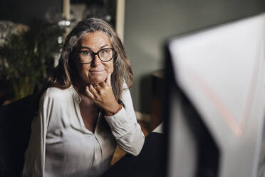 Portrait of female freelancer with disability sitting at desk in home office - MASF42224