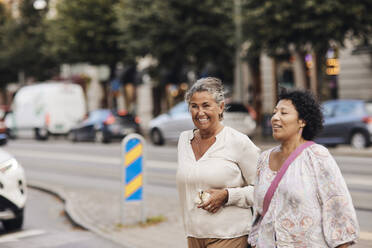 Glückliche Frau beim Spaziergang mit Freundin in der Stadt - MASF42259