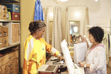 Verkäuferin mit Behinderung, die einer Kundin bei der Online-Zahlung im Geschäft hilft - MASF42270