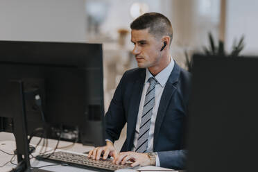 Selbstbewusster junger Geschäftsmann beim Tippen am Computer in einem Büro - MASF42298