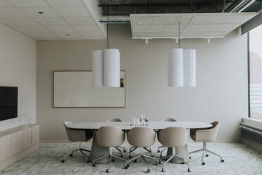 Empty conference table with chairs and pendant light in board room - MASF42332