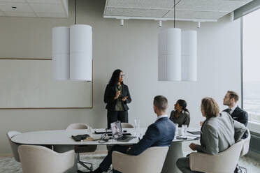 Geschäftsfrau bespricht Strategie mit Kollegen im Sitzungssaal während einer Sitzung - MASF42339