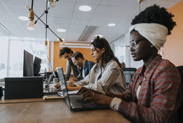 Geschäftskollegen verwenden Laptops bei der Arbeit am Schreibtisch im Büro - MASF42398