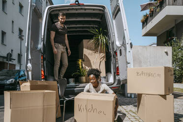 Smiling woman arranging boxes with boyfriend standing in van trunk - MASF42470