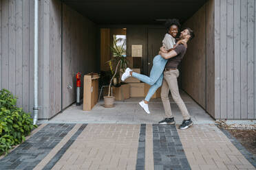 Happy multiracial couple having fun while standing at building entrance - MASF42472