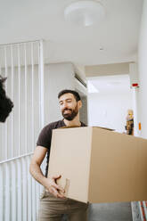 Ein lächelnder Mann hält einen Karton in seinem neuen Zuhause - MASF42480