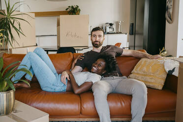 Porträt eines gemischtrassigen Paares, das sich auf dem Sofa im Wohnzimmer seines neuen Hauses entspannt - MASF42493