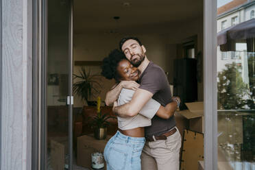 Romantisches Paar umarmt sich mit geschlossenen Augen in seinem neuen Zuhause - MASF42499