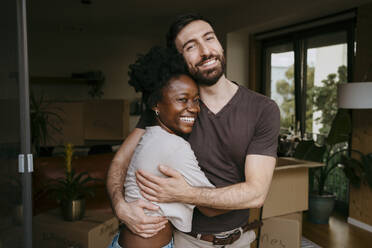 Porträt eines glücklichen Mannes, der seine Freundin in der neuen Wohnung umarmt - MASF42500