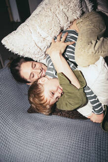 Hohe Winkel Ansicht der glücklichen Frau umarmt Sohn, während auf dem Bett zu Hause liegen - MASF42522