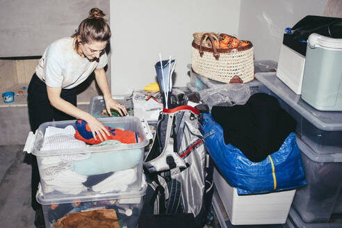Frau beim Sortieren von Kleidung in Containern während des Umzugs eines Hauses - MASF42530