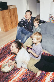 Kinder spielen ein Videospiel, während sie mit ihren Eltern zu Hause sitzen - MASF42540
