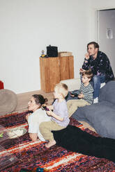 Kinder spielen ein Videospiel, während sie mit ihren Eltern zu Hause sitzen - MASF42541