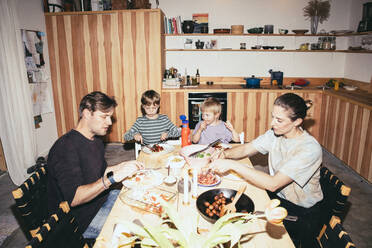 Die Familie isst zu Abend, während sie am Esstisch in der Küche sitzt - MASF42564