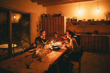 Glückliche Familie genießt Candle-Night-Dinner, während am Esstisch in der Heimat sitzen - MASF42566