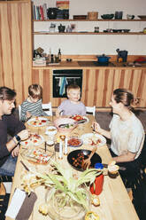 High angle view of happy family having fun while having dinner at dining table in kitchen - MASF42568