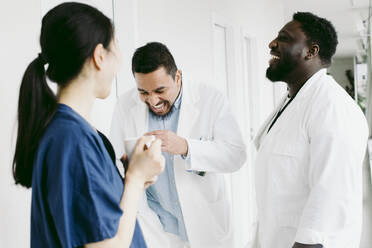 Cheerful multiracial medical team enjoying during coffee break at hospital - MASF42570