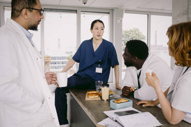 Medical colleagues discussing during lunch break at hospital - MASF42604