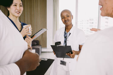 Multiracial healthcare team discussing while standing at hospital - MASF42625