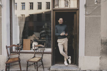 Smiling male entrepreneur leaning on office doorway - MASF42627