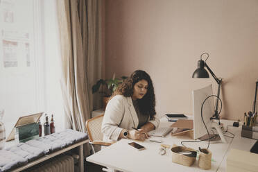 Young businesswoman working while sitting at desk in office - MASF42644