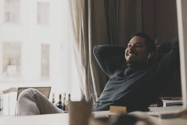 Smiling businessman relaxing while sitting on chair at office - MASF42653