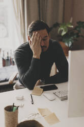 Tired businessman leaning at desk while sitting in office - MASF42655