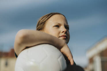 Nachdenkliches Mädchen mit Sportball, das in den Himmel schaut - MASF42692