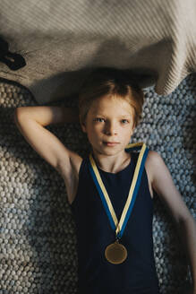 Unmittelbar über dem Porträt eines Jungen, der eine Medaille trägt und zu Hause auf einem Teppich liegt - MASF42731