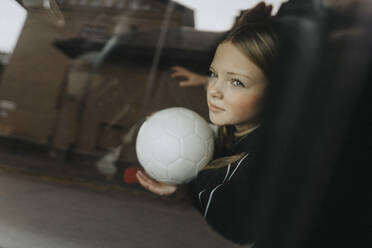 Nachdenkliches Mädchen mit Fußball durch die Scheibe eines Autos gesehen - MASF42742