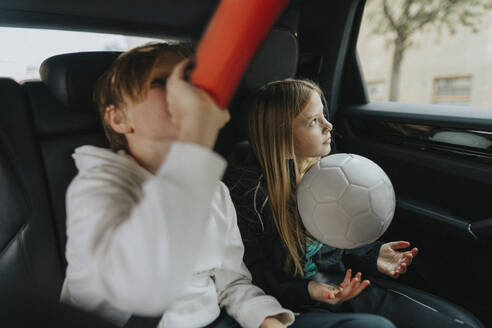 Boy drinking water while sitting with sister in car during weekend trip - MASF42744