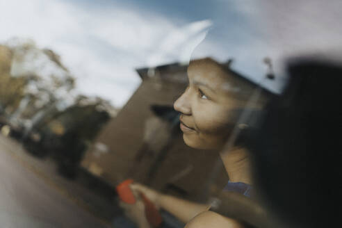 Contemplative teenage girl seen through glass of window - MASF42747