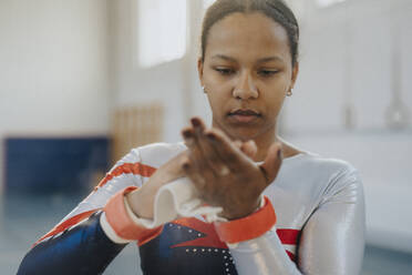 Teenage girl applying chalk powder on hands at gym - MASF42762