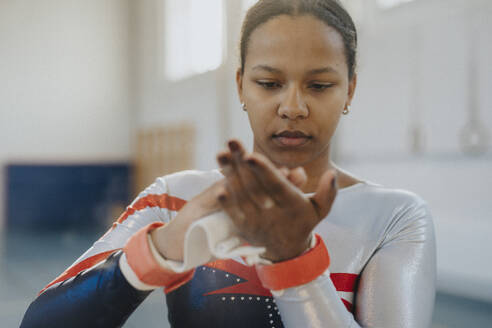 Teenagerin trägt im Fitnessstudio Kreidepulver auf die Hände auf - MASF42762