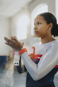 Weibliche Turnerin trägt im Fitnessstudio Kreidepulver auf die Hände auf - MASF42763