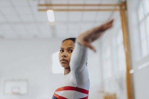 Engagiertes junges Mädchen mit ausgestrecktem Arm bei einer Übung im Fitnessstudio - MASF42770