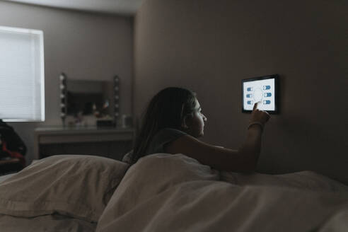 Girl adjusting temperature of bedroom through digital tablet at modern home - MASF42827