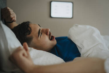 Jugendlicher gähnt auf dem Bett beim Aufwachen am Morgen zu Hause - MASF42829